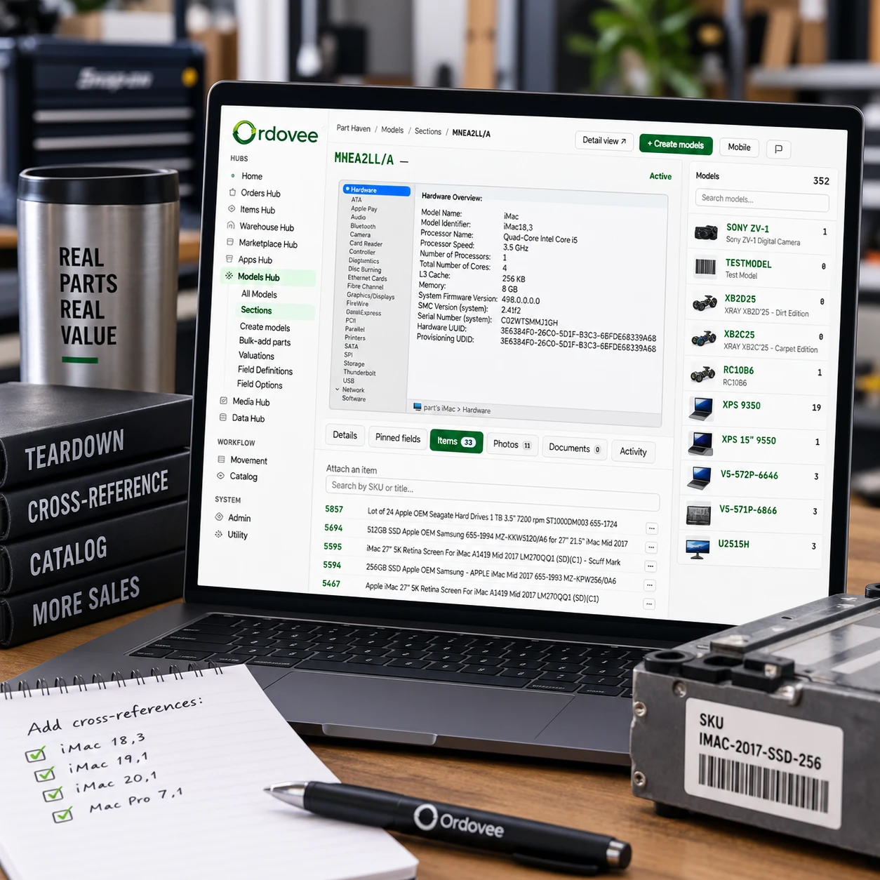 The Ordovee Models hub on a laptop — an iMac model record with its hardware overview, 33 attached items listed by SKU, and the models list beside it — with a notebook checklist of cross-references to add, an Ordovee pen, and a 256 GB SSD labelled with its SKU on the bench.