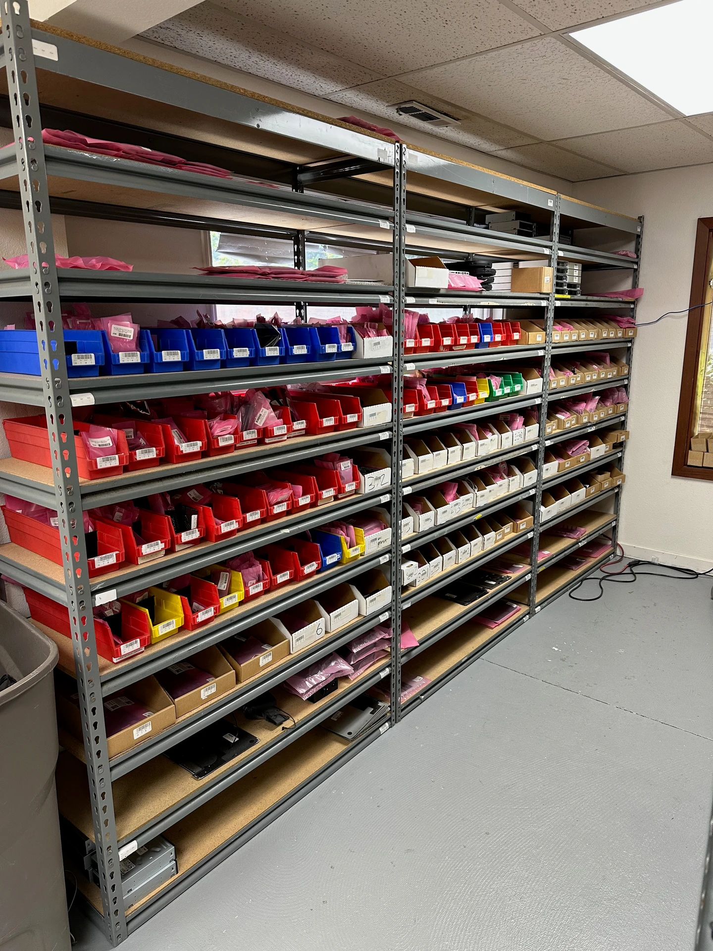 Part Haven's parts room — steel shelving stocked with labeled bins and anti-static bags of components, each spot barcoded.